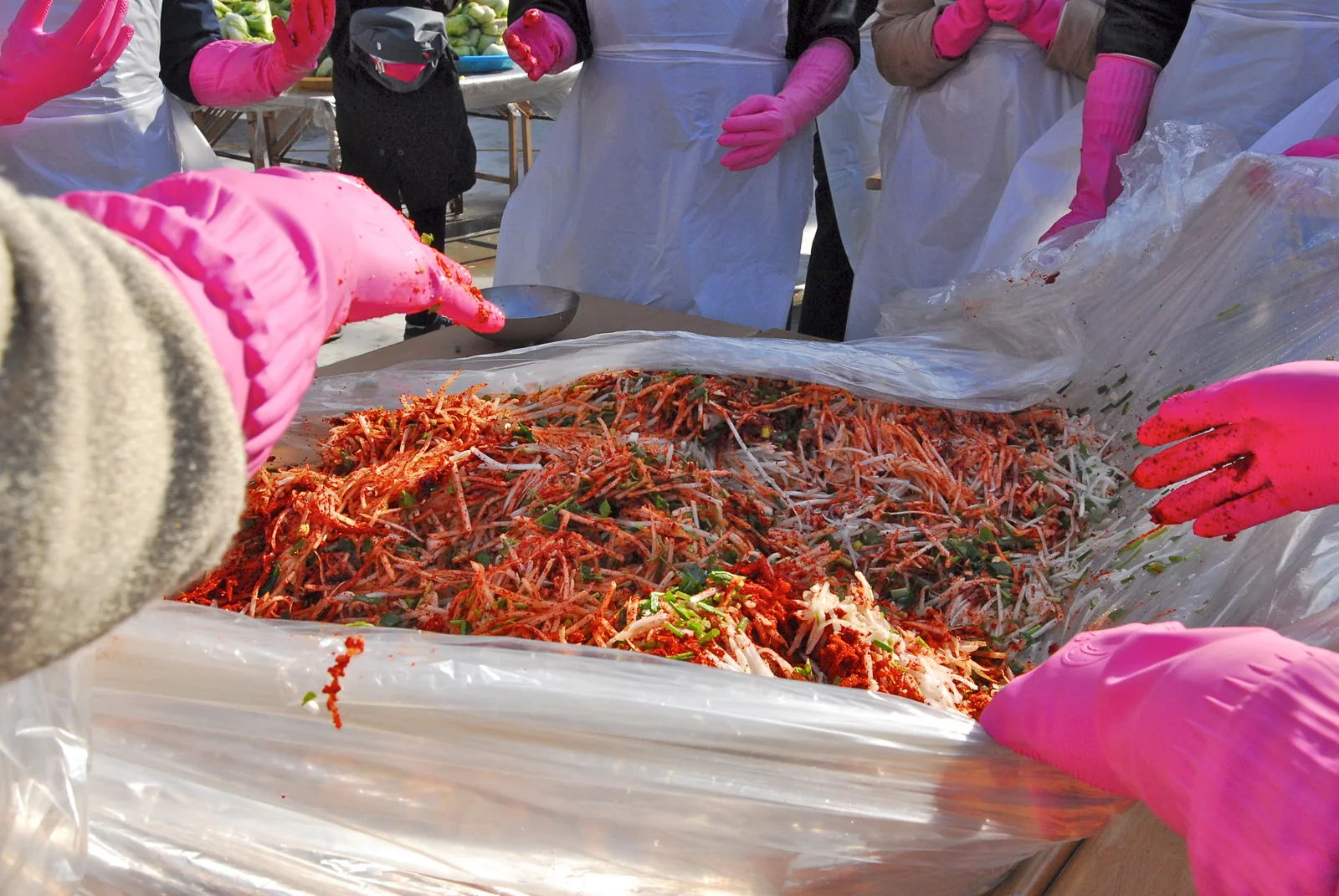 People in pink gloves mixing seasoned radish during winter kimjang work in Gaemi Village